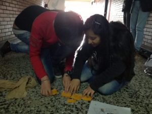 Dos estudiantes observando las tarjetas que están sobre el piso que corresponden a la actividad: En los zapatos de ...